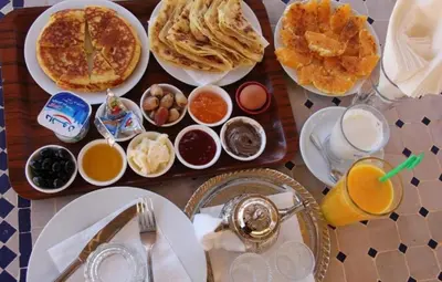 a table with breakfast foods and drinks on it at Holiday Desert Camp in Merzouga
