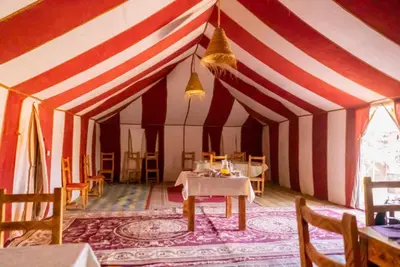 a tent with a table and chairs in it at Holiday Desert Camp in Merzouga