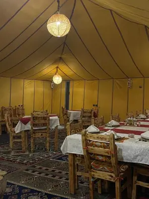 a large tent with tables and chairs in it at Merzouga Luxury Dunes Camp in Merzouga