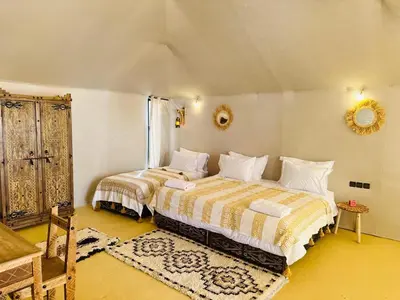 a bedroom with two beds and a mirror on the wall at Luxury Sahara Camp in Merzouga