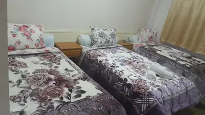 two beds in a room with floral sheets and pillows at Hotel Opéra Azrou in Azrou
