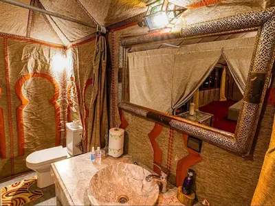 a bathroom with a sink and a toilet and a mirror at Gorgeous Luxury Camp in Merzouga