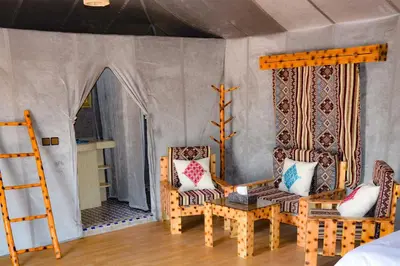 a room with two chairs and a table and a bed at Merzouga desert Luxury Camp in Merzouga