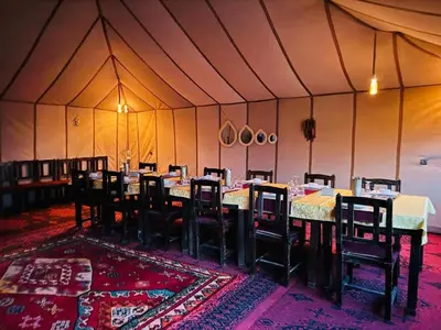 a dining room with tables and chairs in a tent at Merzouga Luxury Tent in Merzouga