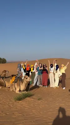 a group of people in the desert with a camel at Dream Luxury Majestic Camp in Merzouga