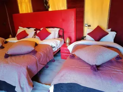 a bedroom with two beds with red headboards at Africa Magic Camp in Merzouga