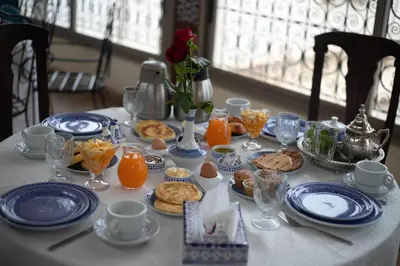 a table with blue and white plates of food and orange juice at La Perle de La Medina in Fès