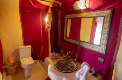 a bathroom with a toilet and a sink and a mirror at Merzouga Luxurious Camp in Merzouga
