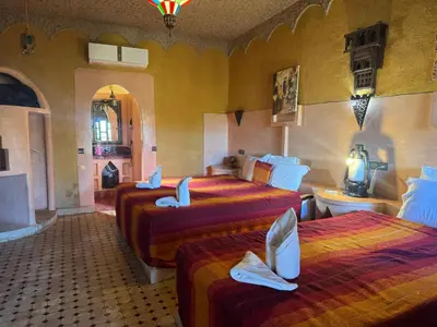 a hotel room with three beds and a bathroom at Riad Ksar Merzouga in Merzouga