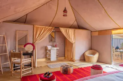 a bedroom in a tent with a table and a desk at Alibaba Merzouga Camp in Merzouga