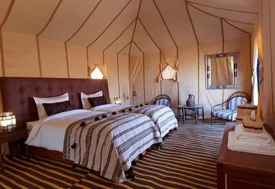 a bedroom with two beds in a tent at Royal Sands Camp in Merzouga
