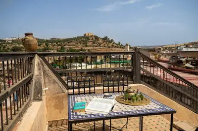 a table on top of a balcony with a book at Dar Authentic Fes - familly hosting in Fès