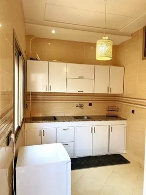 a kitchen with white cabinets and a sink at Appartement calme top in Fès