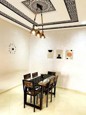 a dining room table with chairs and a clock on the wall at Appartement calme top in Fès