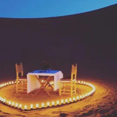 a table and two chairs with lights around it at khayma Camp And Actevities in Merzouga