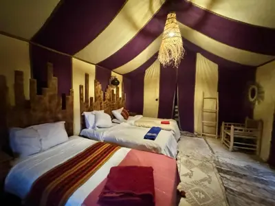 two beds in a room with purple and white walls at Best Luxury Camp in Merzouga