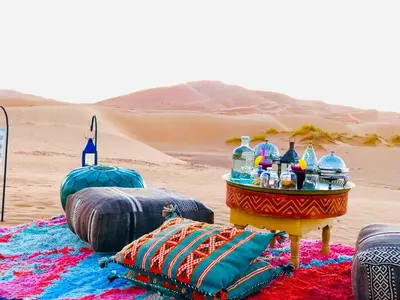 a table in the middle of a desert with drinks at Aurum Dunes Luxury Camp in Merzouga