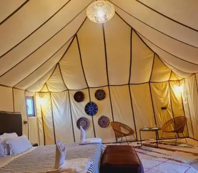 a tent with two chairs and a bed in a room at Luxurious Desert Camp in Merzouga