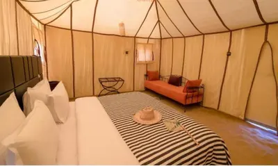 a tent room with a bed with a hat on it at Luxurious Desert Camp in Merzouga