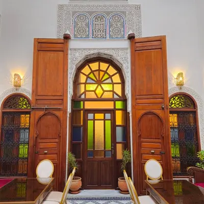 a room with three wooden doors with stained glass at Riad Fes Miracle in Fès al Bali