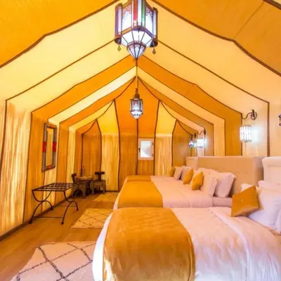 a large room with two beds and a chandelier at desert tribe luxury camp in Merzouga