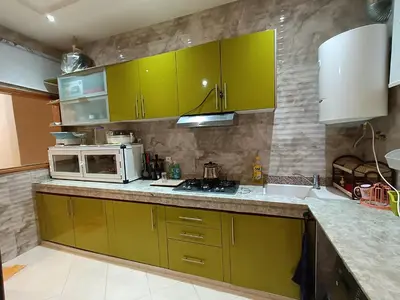 a kitchen with green cabinets and a microwave at Appartement a Meknès-Hamria in Meknès