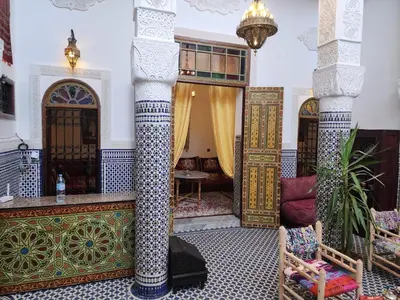 a room with two beds and a table in a building at Dar Zerbtana Chambre chaoune in Fès
