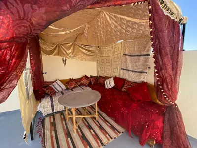 a room with a bed with a red couch and a table at Dar Zarbtana Chambre Marrakech in Fès