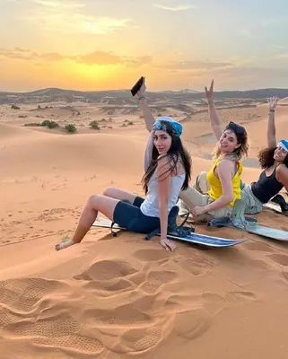 a group of women sitting in the desert at Chic Boheme Camp in Merzouga
