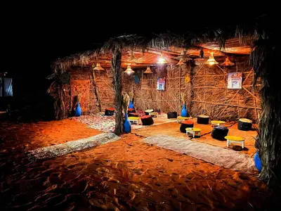 a room with a straw hut with trees and couches at Morocco wonderland in Merzouga