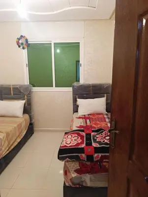 a room with two beds and a window and a door at Appartement tradimoderne in Mrhila