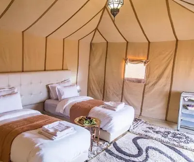 a room with two beds in a tent at Merzouga Hamza Luxury Camp in Merzouga