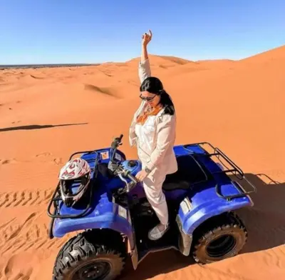 a woman standing on a wheeler in the desert at Merzouga Sardegna Luxury Camp in Merzouga
