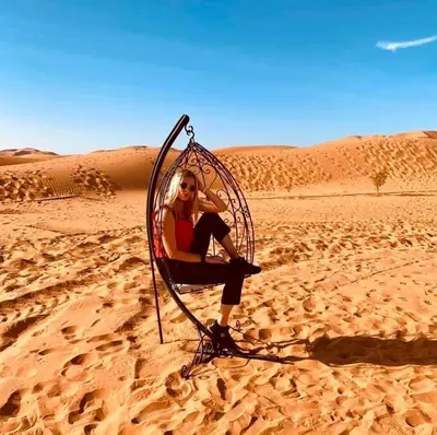 a woman sitting in a chair in the desert at Une Nuit de Rêve dans une Tente de Luxe - Expérience en plein désert ! in Merzouga