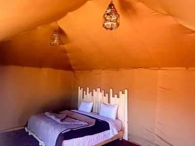 a bedroom with a bed in a tent at Eco Merzouga luxury camp in Merzouga
