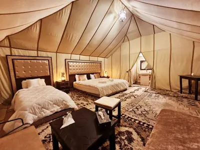 a bedroom with two beds in a tent at Adrar desert camp in Merzouga