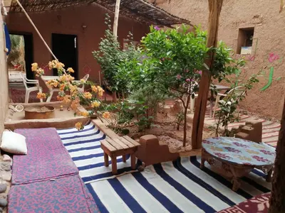 a patio with a table and benches and trees at Dar itran in Mhamid