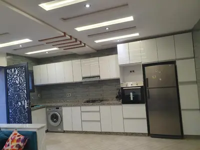 a large kitchen with white cabinets and a refrigerator at Dar diafa in Imouzzer Kandar