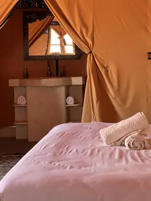 a bed in a tent with a towel on it at Finest Luxury Camp in Merzouga
