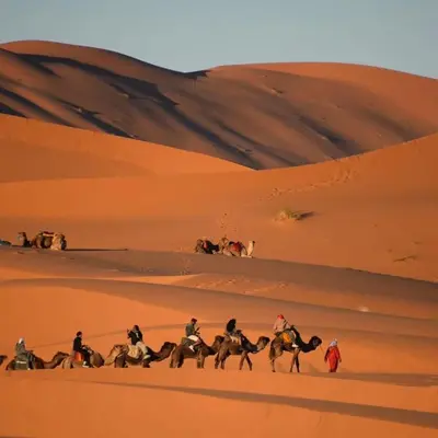 a group of people riding horses in the desert at Happy luxury camp in Merzouga