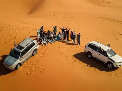 a group of people standing in the sand in a desert at Merzouga Sahara Top Camp in Merzouga