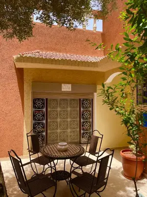 a patio with a table and chairs in front of a building at Dyafat Abla in Ouarzazate