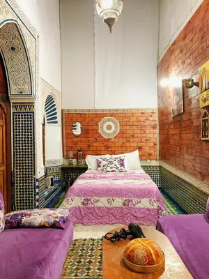a bedroom with two beds and a table in it at Dar lmallouki in Meknès