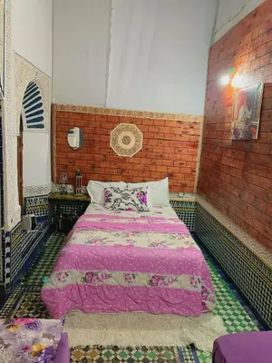 a bedroom with a large bed in a brick wall at Dar lmallouki in Meknès