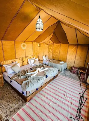 a bedroom with two beds in a tent at Luxury Merzouga Desert Camp in Merzouga