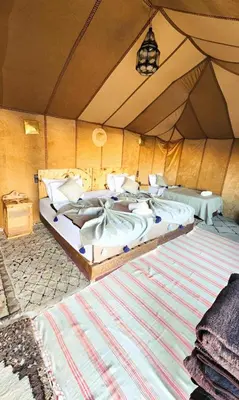 a bedroom with two beds in a tent at Luxury Merzouga Desert Camp in Merzouga