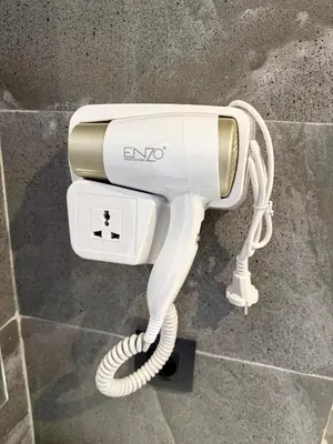 a white electric hair dryer sitting on a wall at Appartement centre-ville avec Wifi fibre optique in Fès