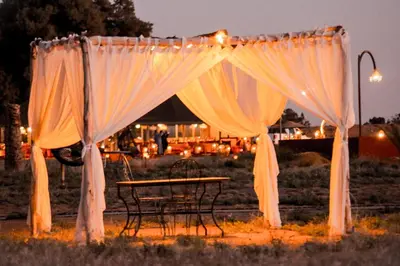 a table and chairs under a tent with curtains at Serenity Sky Luxury Camp in Merzouga