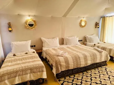 a bedroom with two beds and a mirror on the wall at Sania Luxury Camp in Merzouga