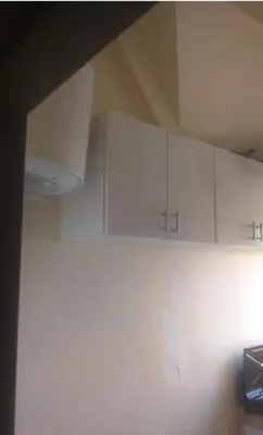a kitchen with white cabinets on the wall at Casa De La Mama chauffée cosy et climatisée 3 pièces Ifrane sous la neige in Ifrane